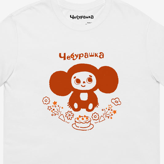 White unisex tee featuring minimalist brown Cheburashka with a birthday cake. Closeup photo. www.cheburashkashop.com