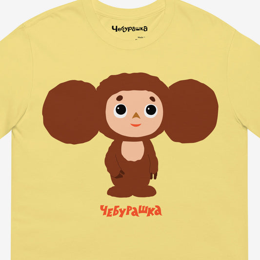 Yellow unisex adult T-shirt featuring Soviet cartoon shy Cheburashka. Minimalist large bright print design. With Чебурашка logo below and on the necktag. Closeup photo.