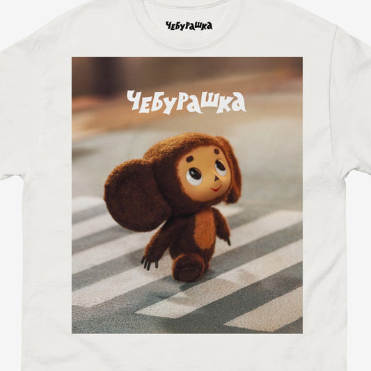 Cheburashka on road zebra crossing. Still frame from old original Soviet cartoon. With logo Чебурашка. Closeup.
