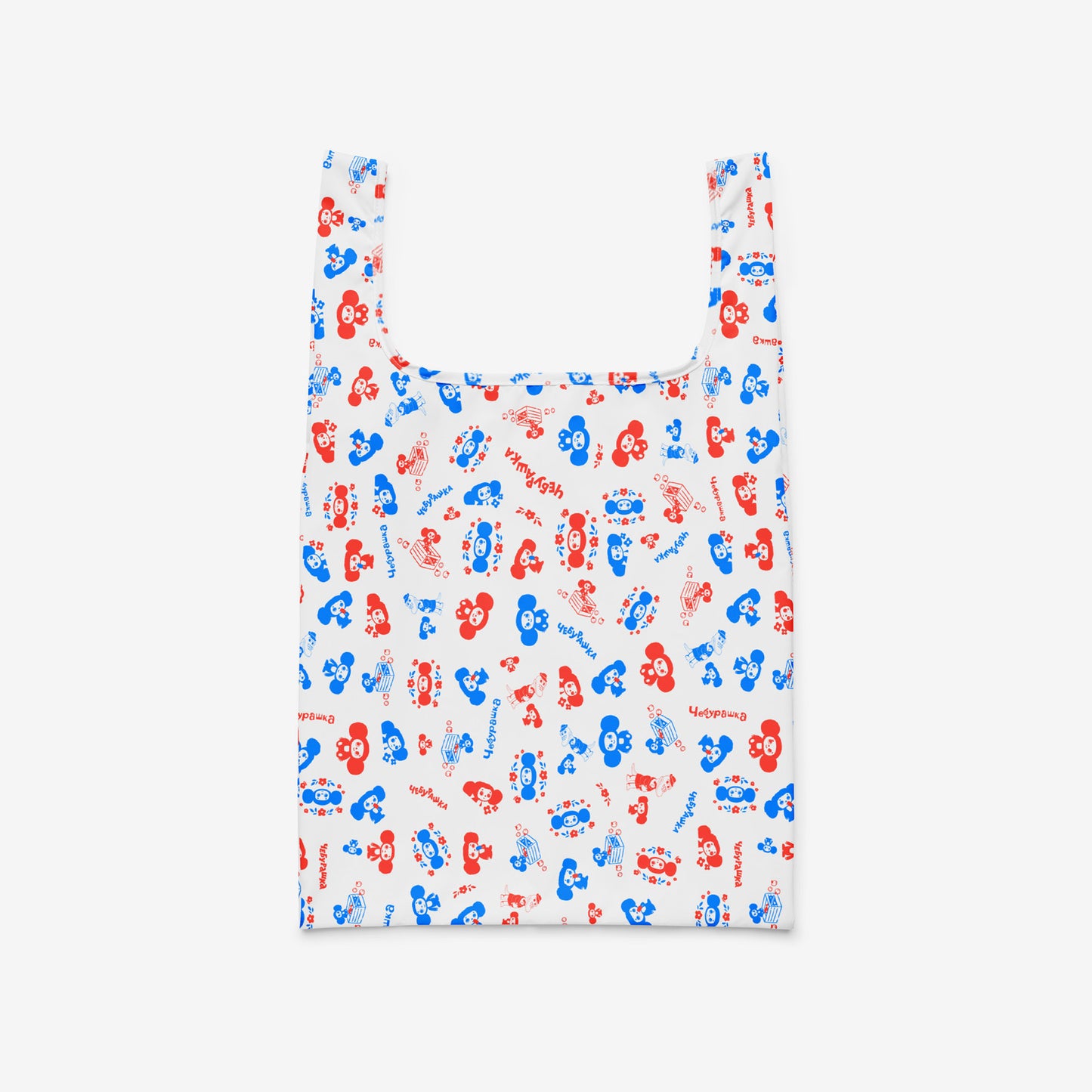 A reusable folding shopping bag with a white background and an all-over pattern of red and blue Soviet cartoon character Cheburashka. Front.