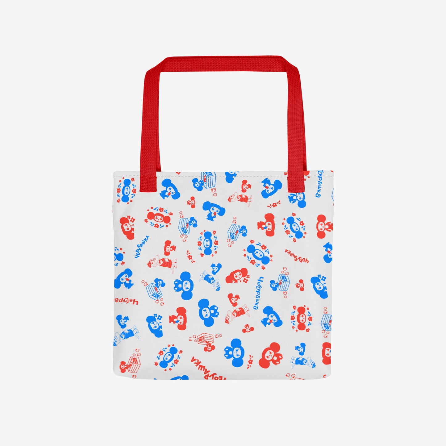 A white tote bag with a red shoulder strap, featuring an all-over pattern of red and blue original Soviet cartoon characters Cheburashka. Front photo.