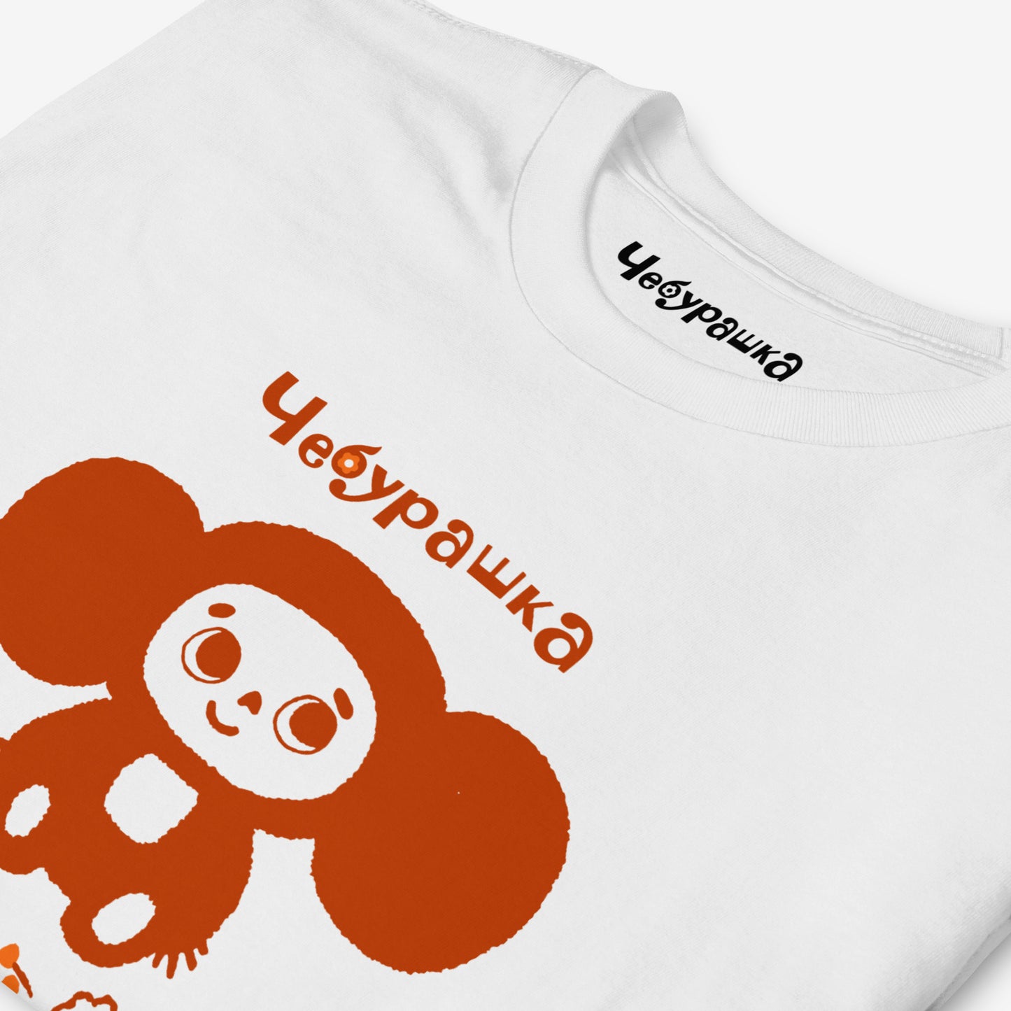 White unisex tee featuring minimalist brown Cheburashka with a birthday cake.  Closeup print details. www.cheburashkashop.com