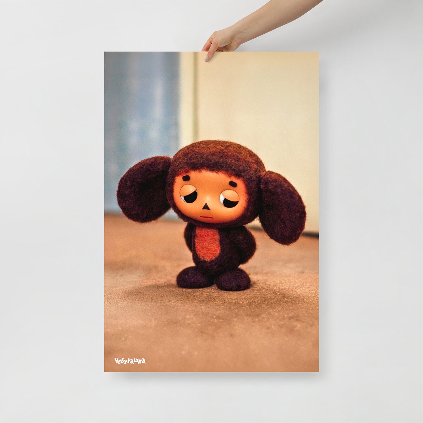 Hand holding large 61x91cm poster with original Sad Cheburashka from Soviet cartoon. With logo Чебурашка.