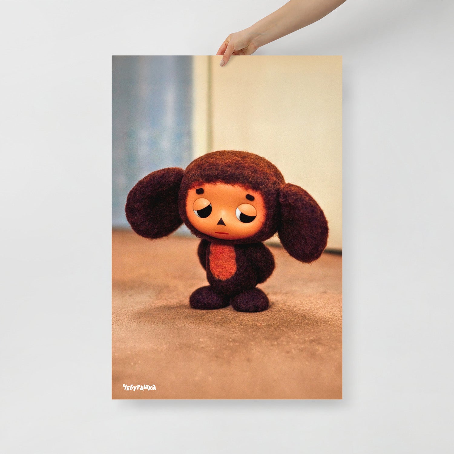 Hand holding large 61x91cm poster with original Sad Cheburashka from Soviet cartoon. With logo Чебурашка.