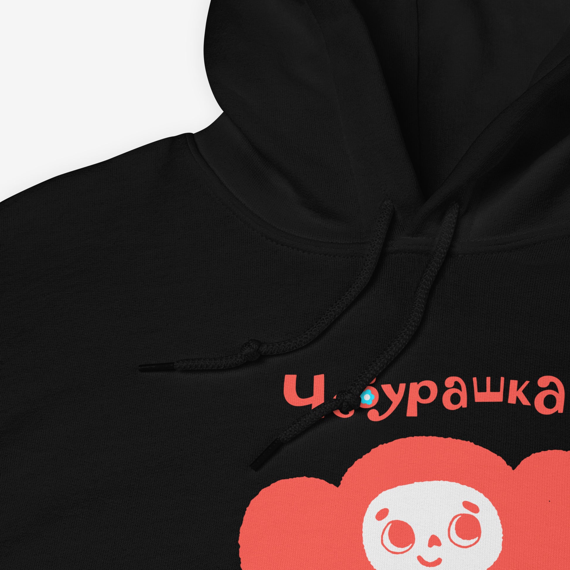 Black unisex hoodie featuring minimalist red Cheburashka with a birthday cake. Cute red-pinkish color. With Чебурашка logo on the necktag label. Closeup print photo. www.cheburashkashop.com
