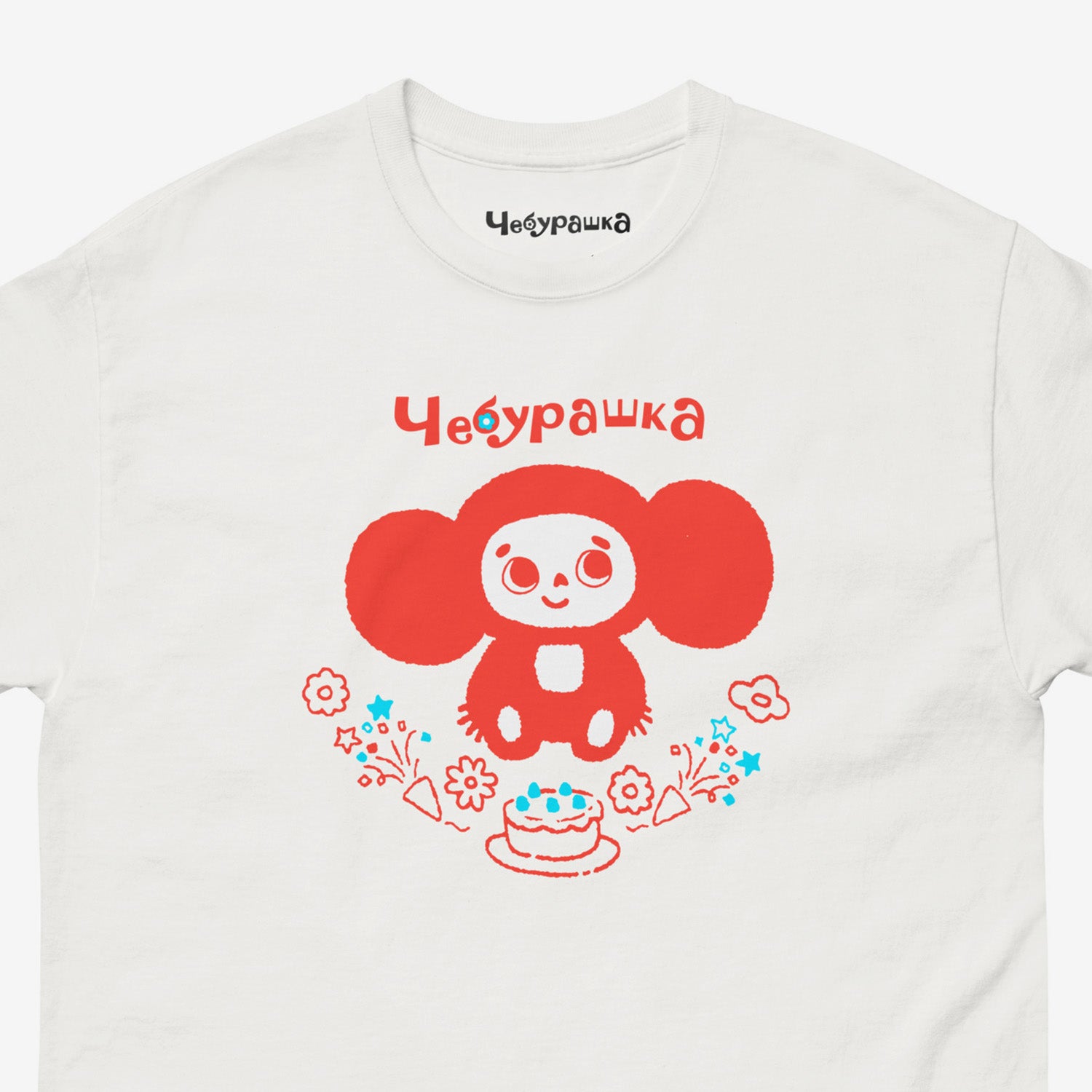 White unisex tee featuring minimalist red graphic of Cheburashka with a birthday cake. Cute red-pinkish color. Closeup photo with Чебурашка logo on necktag. www.cheburashkashop.com