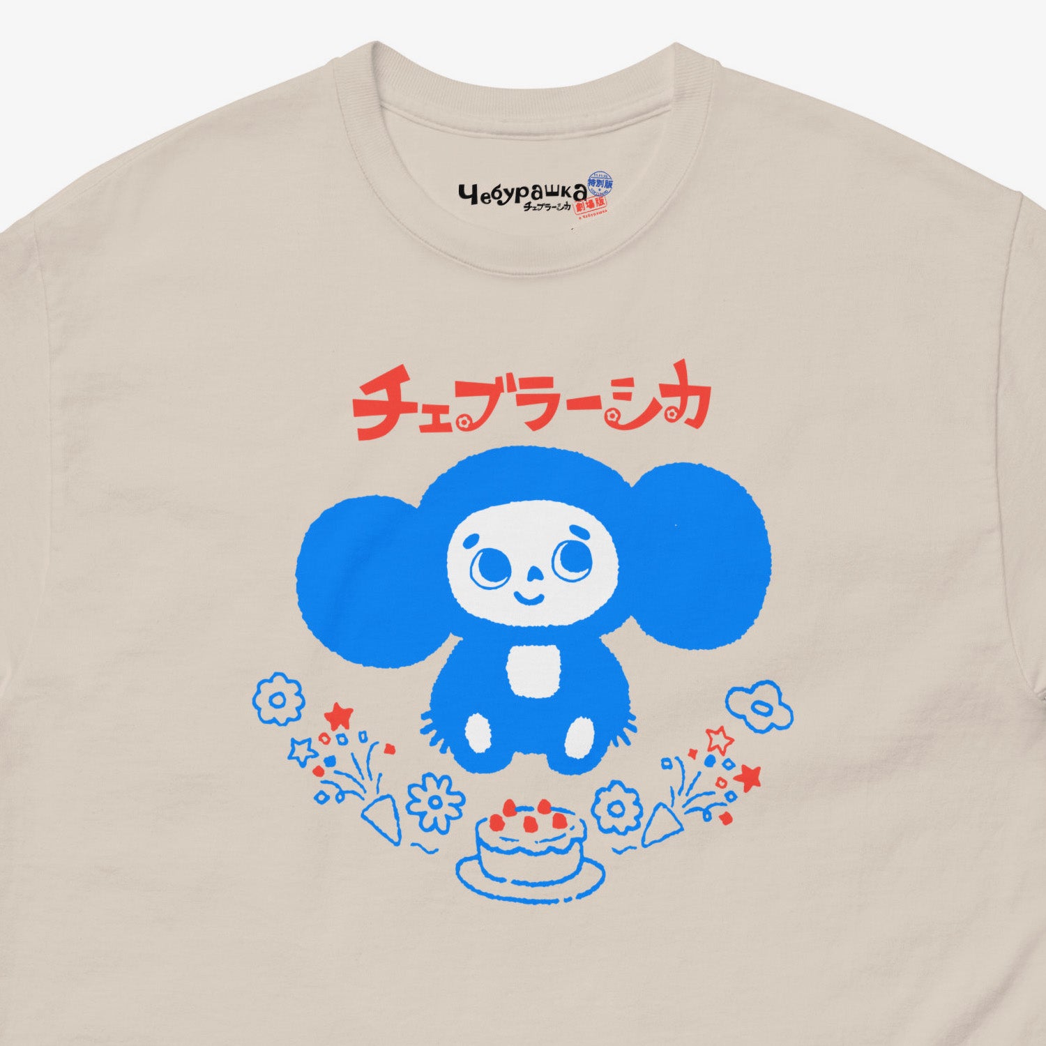 Beige unisex adult tee featuring minimalist Cheburashka with a birthday cake. Japanese edition with text チェブラーシカ. Cute baby-blue print color. Closeup photo with branded necktag logo Чебурашка. www.cheburashkashop.com