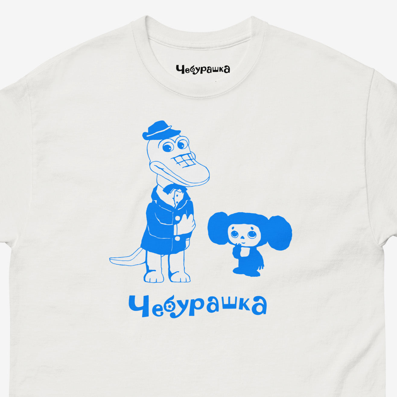 White unisex adult tee featuring minimalist graphic of Cheburashka with his friend Gena the crocodile and text Чебурашка. Cute light-blue print color. With branded necktag logo Чебурашка. Closeup photo. www.cheburashkashop.com