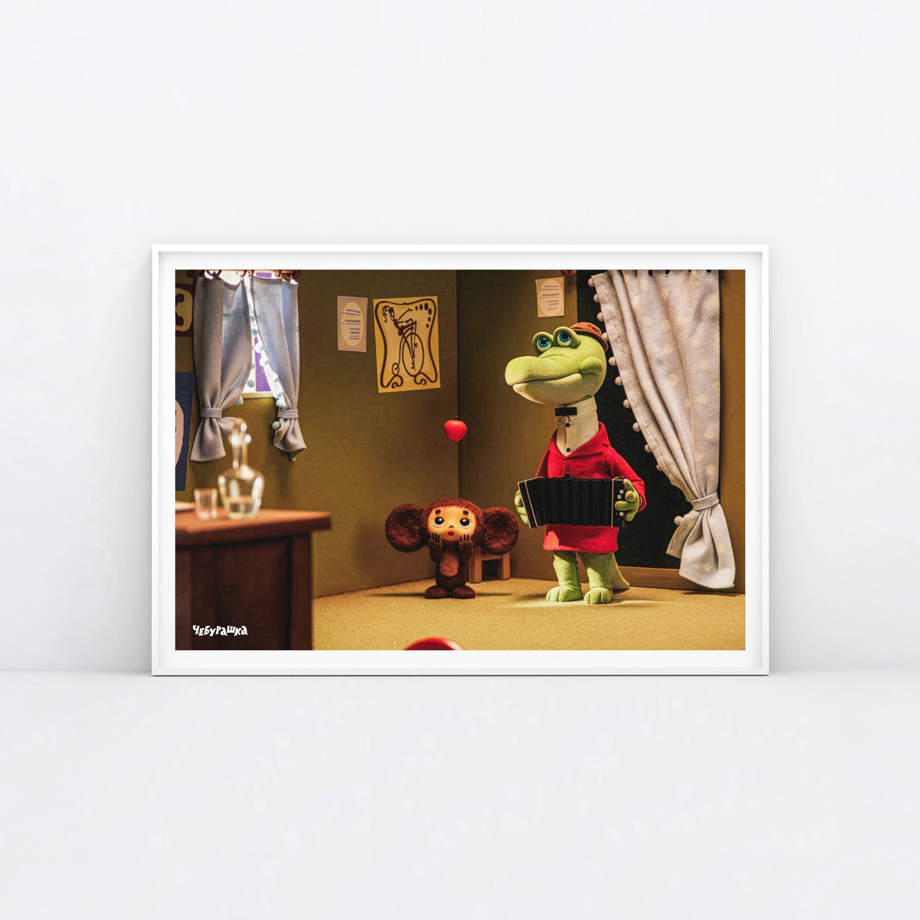 A large framed art print featuring a scene from the Soviet cartoon Cheburashka, showing Cheburashka playing with apples and his friend Gena the crocodile playing accordion in a room. With Чебурашка logo on the bottom left side.