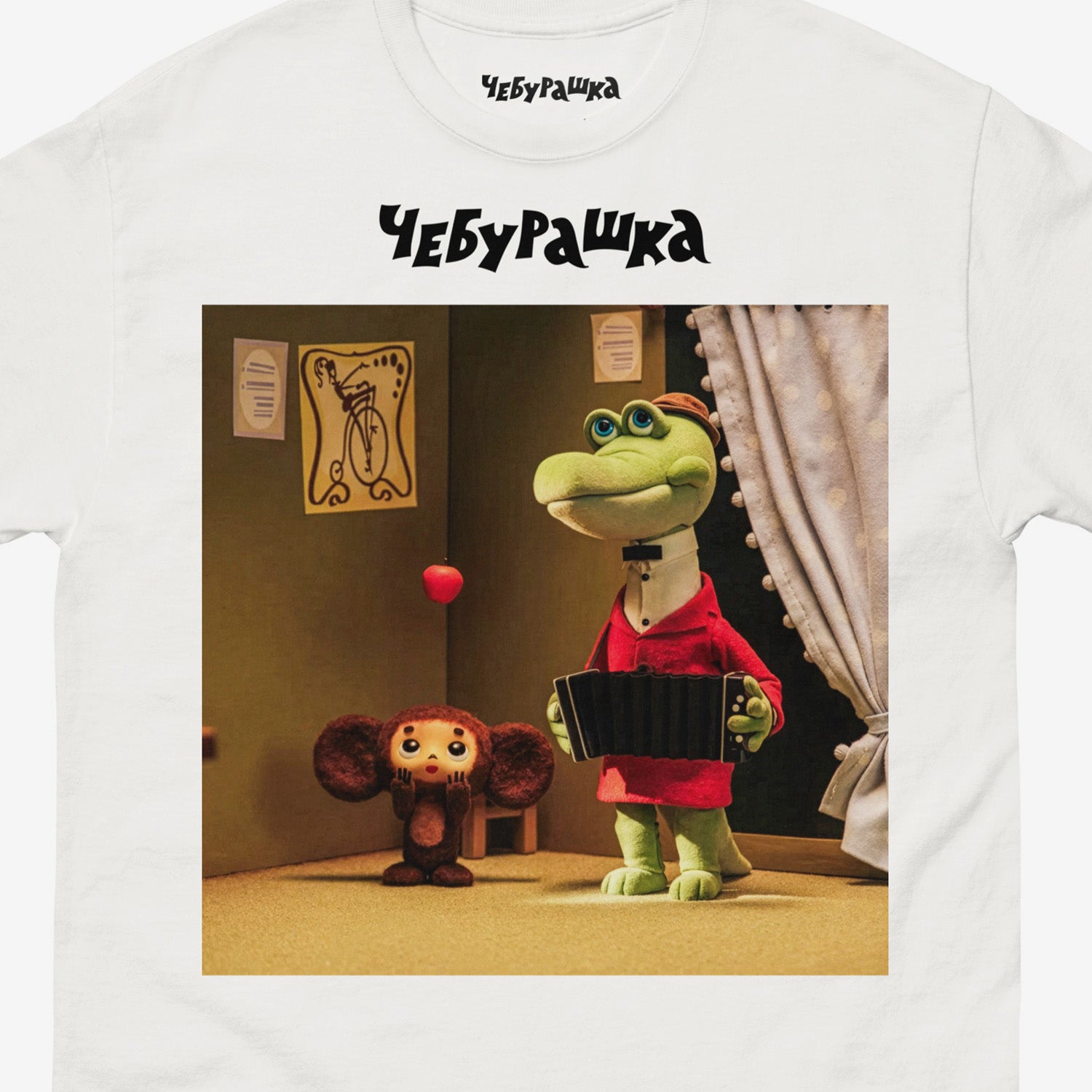 White unisex T-shirt featuring a scene from the Soviet cartoon Cheburashka, showing Cheburashka playing with apples and his friend Gena the crocodile playing accordion in a room. With Чебурашка logo above the image. Closup.