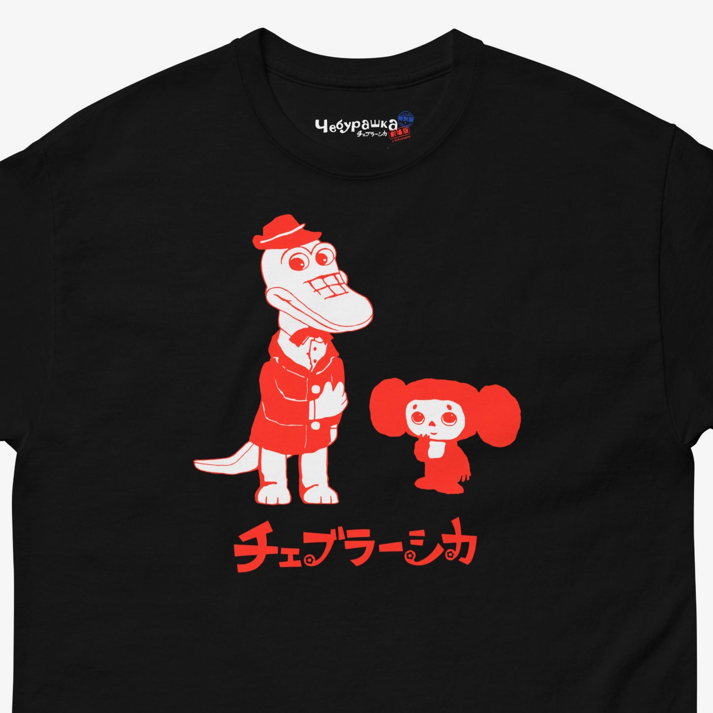 Black unisex adult tee featuring minimalist red graphic of Cheburashka with his friend Gena the crocodile. Japanese edition with text チェブラーシカ. Cute red-pinkish print color. Branded necktag logo Чебурашка. Closeup photo. www.cheburashkashop.com