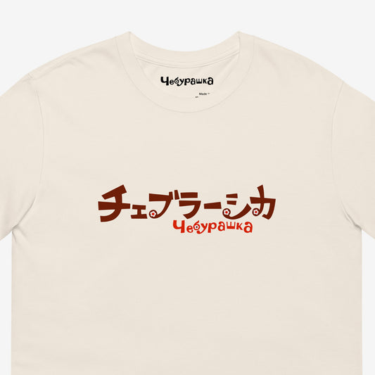 A beige short-sleeve unisex Cheburashka, original Soviet cartoon Tee with a brown チェブラーシカ logo in japanese and a smaller 'Чебурашка' logo in russian underneath. Closeup.
