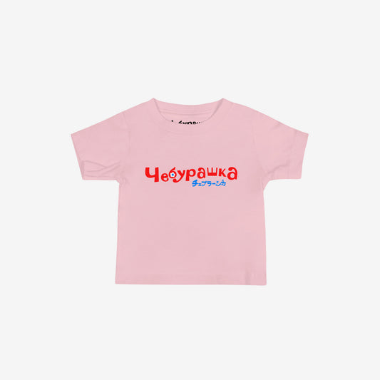 A light pink short-sleeve unisex Cheburashka, original Soviet cartoon baby Tee with a red and blue 'Чебурашка' logo in russian and smaller underneath logo in japanese チェブラーシカ.