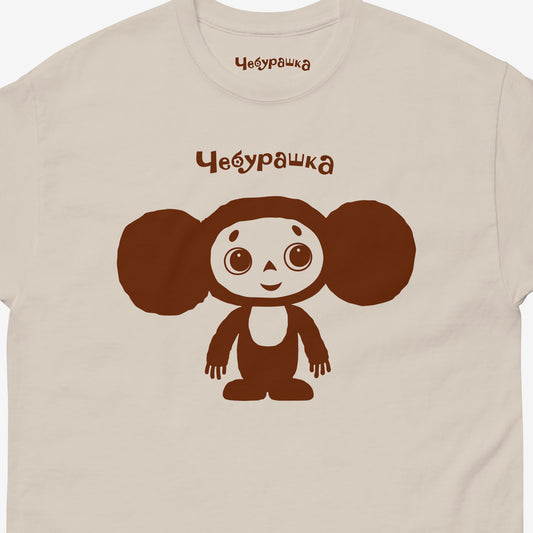 Beige unisex adult T-shirt featuring Soviet cartoon Cheburashka, standing and smiling. Minimalist one-color design. With Чебурашка logo above the image. Closeup photo.