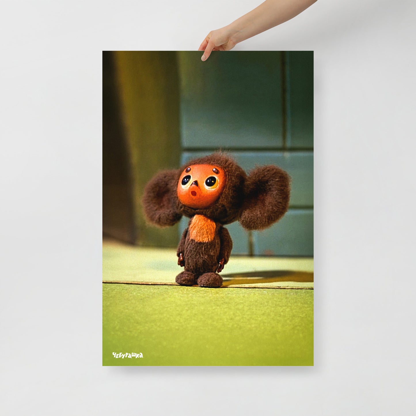Hand holding large 61x91cm unframed poster with original surprised Cheburashka from old Soviet cartoon. With logo Чебурашка.
