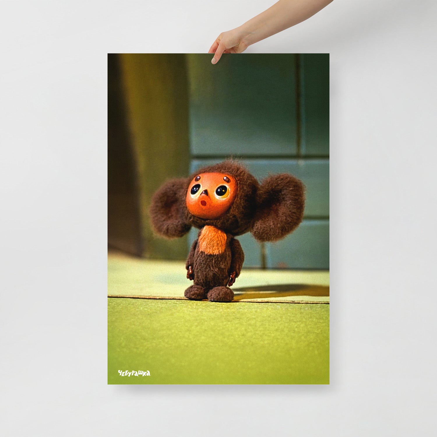 Hand holding large 61x91cm unframed poster with original surprised Cheburashka from old Soviet cartoon. With logo Чебурашка.