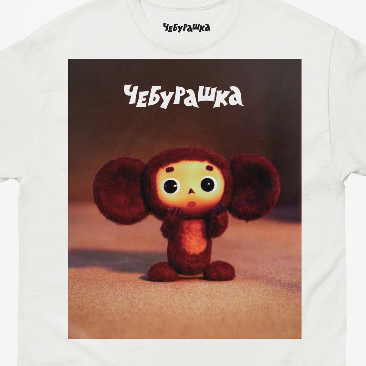 White unisex T-shirt with large print of original surprised Cheburashka from Soviet cartoon. With logo Чебурашка. Closeup photo.