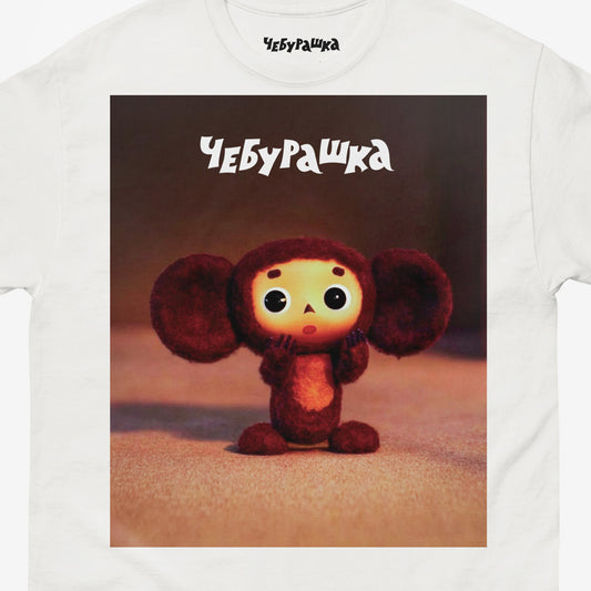White unisex T-shirt with large print of original surprised Cheburashka from Soviet cartoon. With logo Чебурашка. Closeup photo.