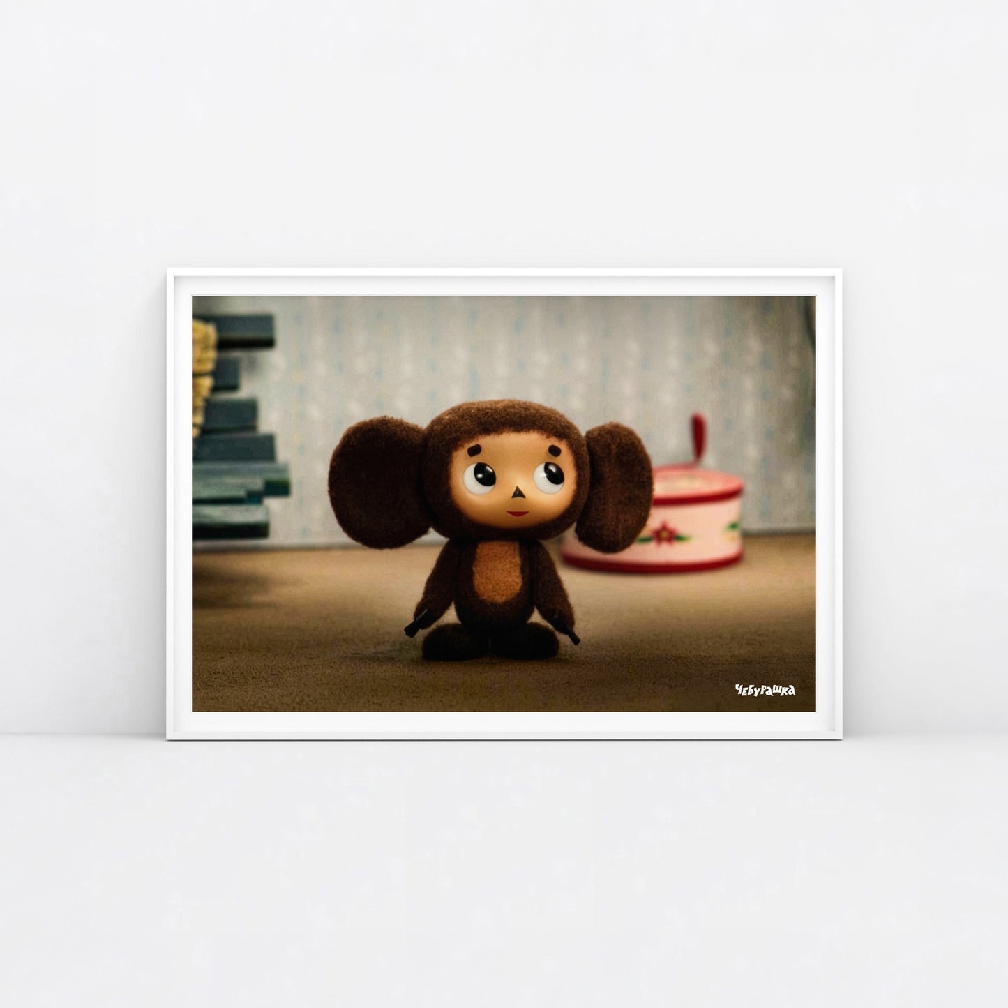 Large 91x61cm poster with original Soviet cartoon character Cheburashka standing cute and curious. Featuring Чебурашка logo at the bottom left. Framed.