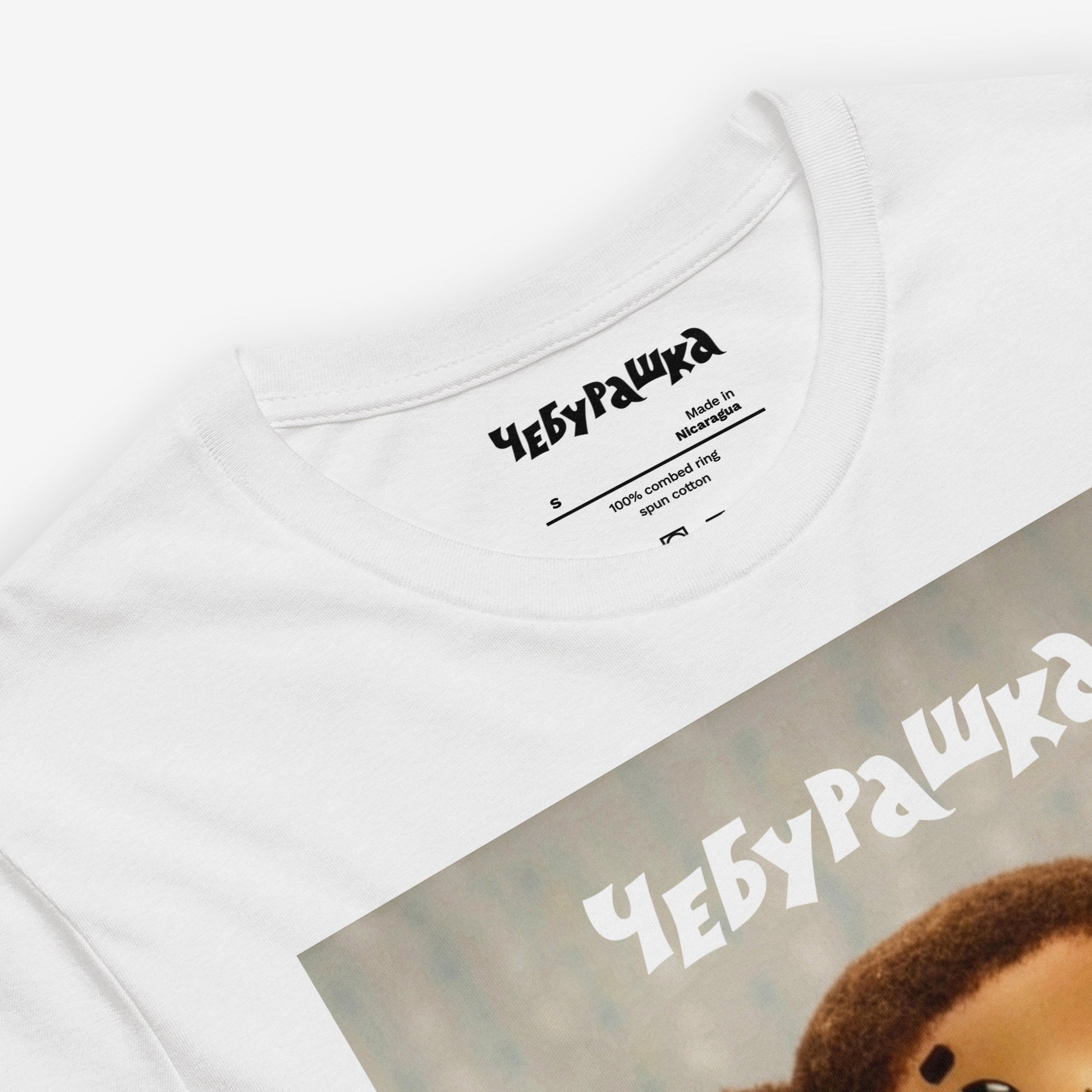 Brown unisex T-shirt with large print of original Soviet cartoon character Cheburashka standing cute and curious. Featuring Чебурашка logo at the of the print. Closeup print details.