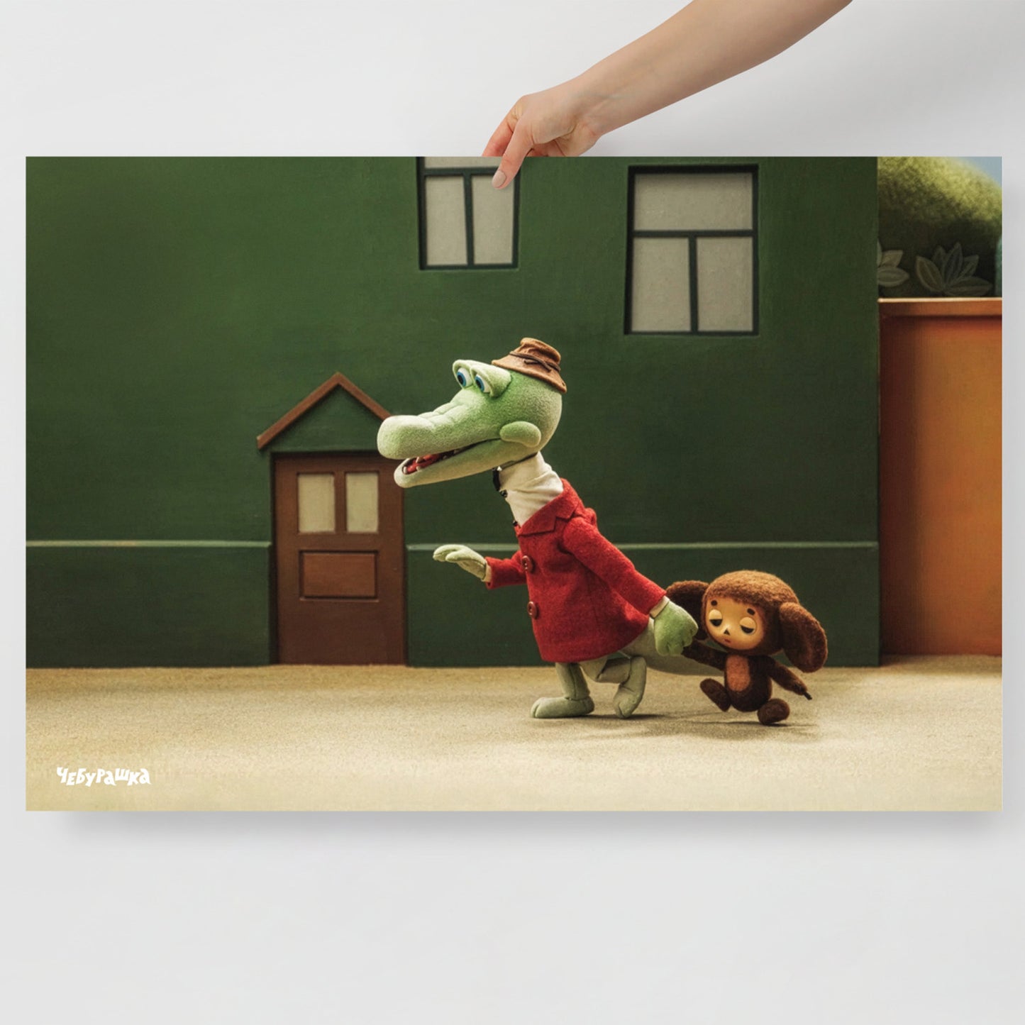 Hand holding large 91x61cm poster with Gena leading Cheburashka. Still frame from old original Soviet cartoon. With logo Чебурашка.