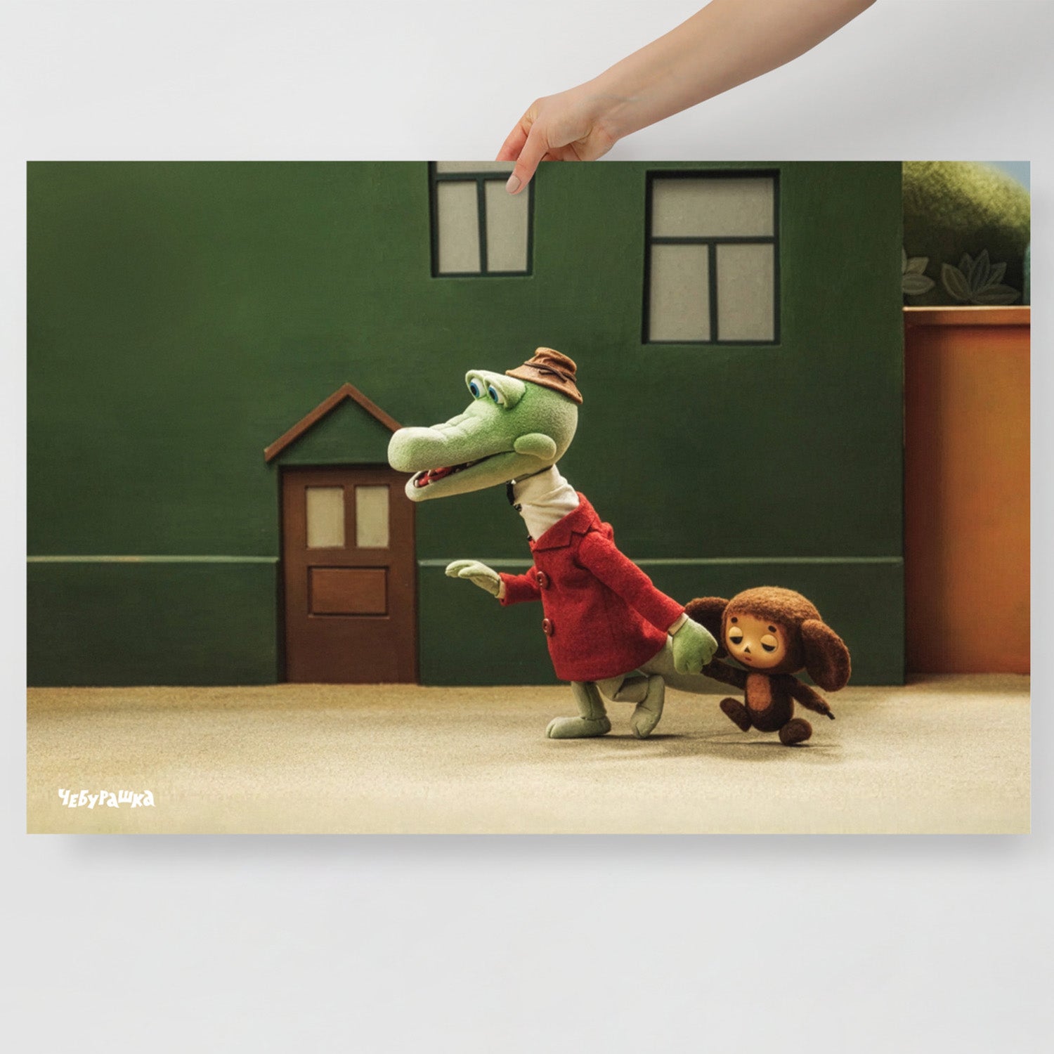 Hand holding large 91x61cm poster with Gena leading Cheburashka. Still frame from old original Soviet cartoon. With logo Чебурашка.