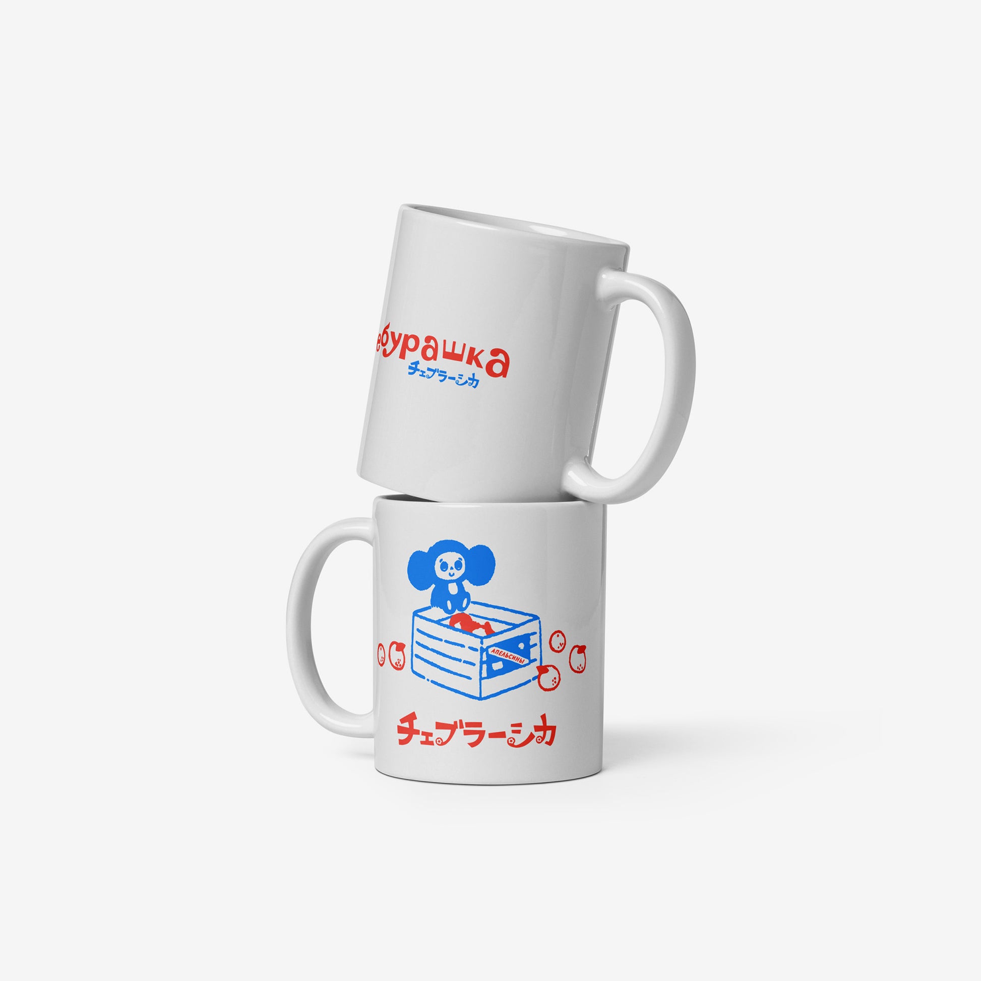 White coffee cup with Cheburashka sitting on a box of oranges and チェブラーシカ logo in red. Back and front.