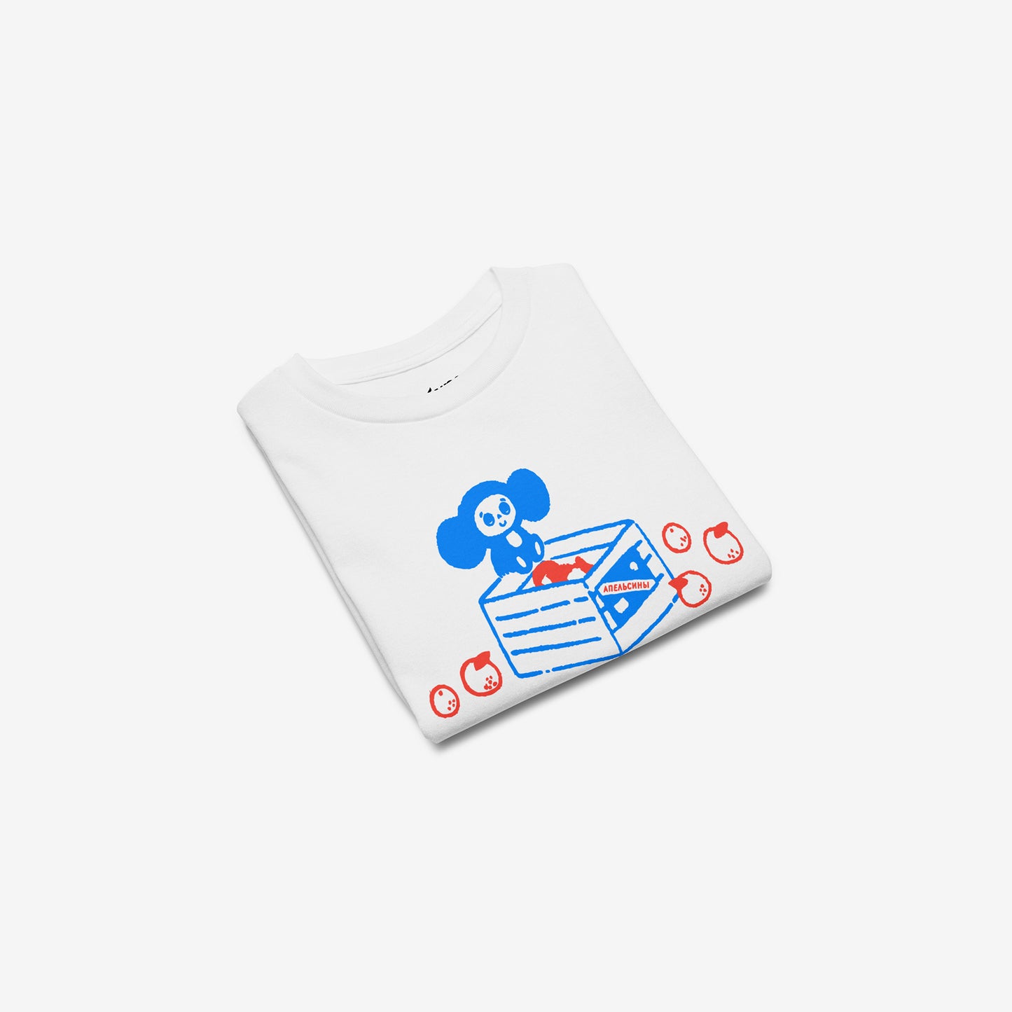 White unisex youth T-shirt with original Soviet cartoon character Cheburashka sitting on a box of oranges and チェブラーシカ logo in red. Folded.