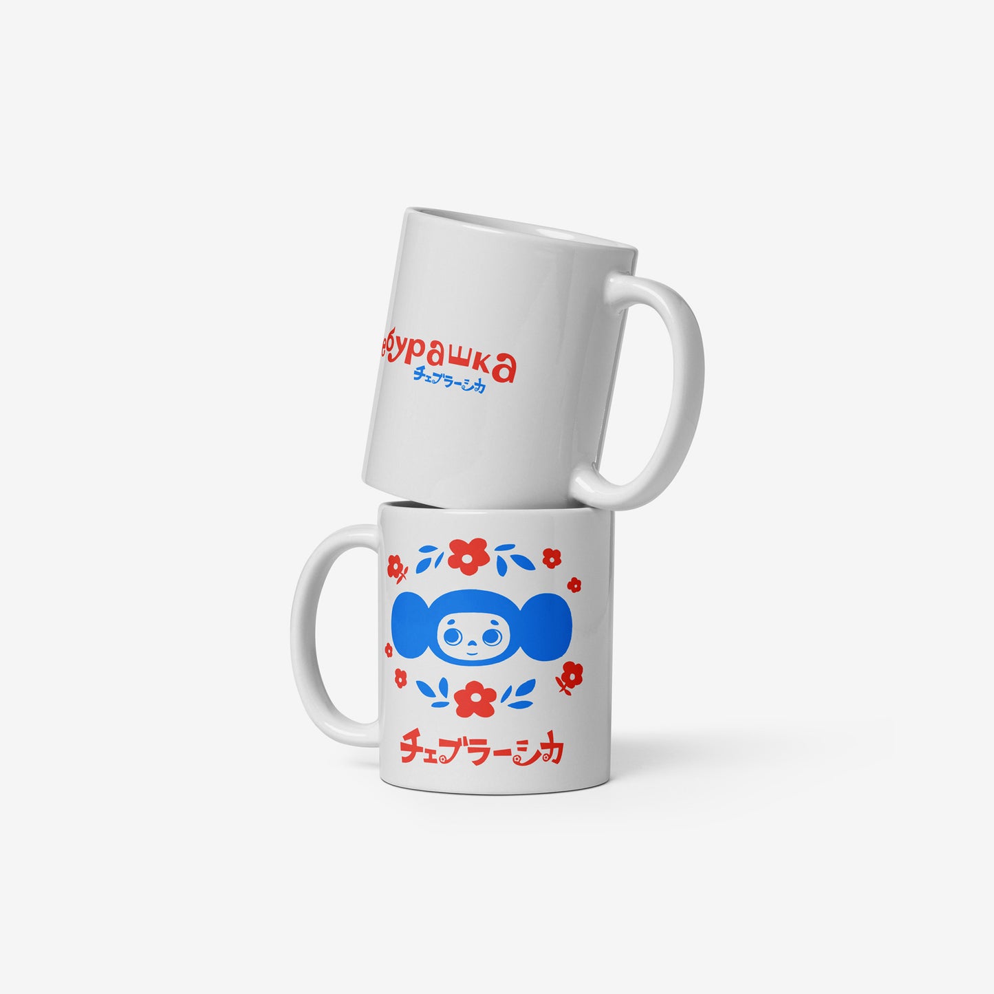 White coffee cup with Cheburashka among a pattern of flowers and チェブラーシカ logo. Two similar mugs stacked on each other with front and back seen.