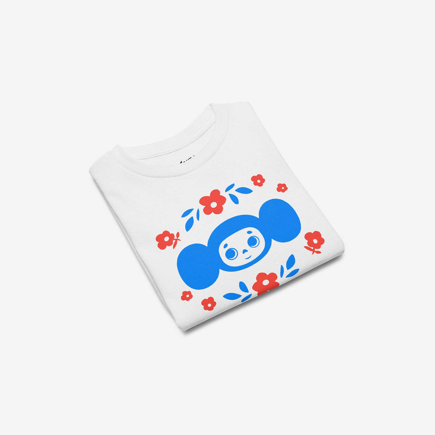 White unisex youth T-shirt with original Soviet cartoon character Cheburashka among a pattern of flowers and with logo in japanese チェブラーシカ. Folded.