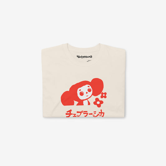 Beige unisex T-shirt with minimalist graphic of Cheburashka with flowers and チェブラーシカ japanese logo in red. Folded.