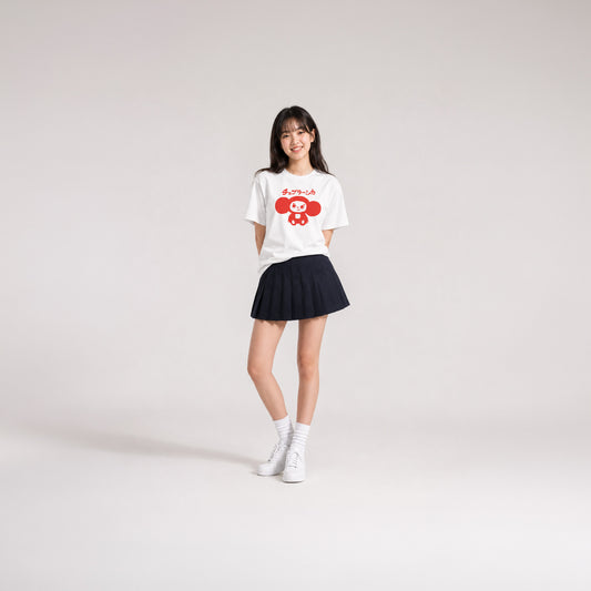 Japanese school girl model wearing skirt and white unisex youth T-shirt with minimalist graphic of original smiley Soviet cartoon character Cheburashka and チェブラーシカ logo in red.
