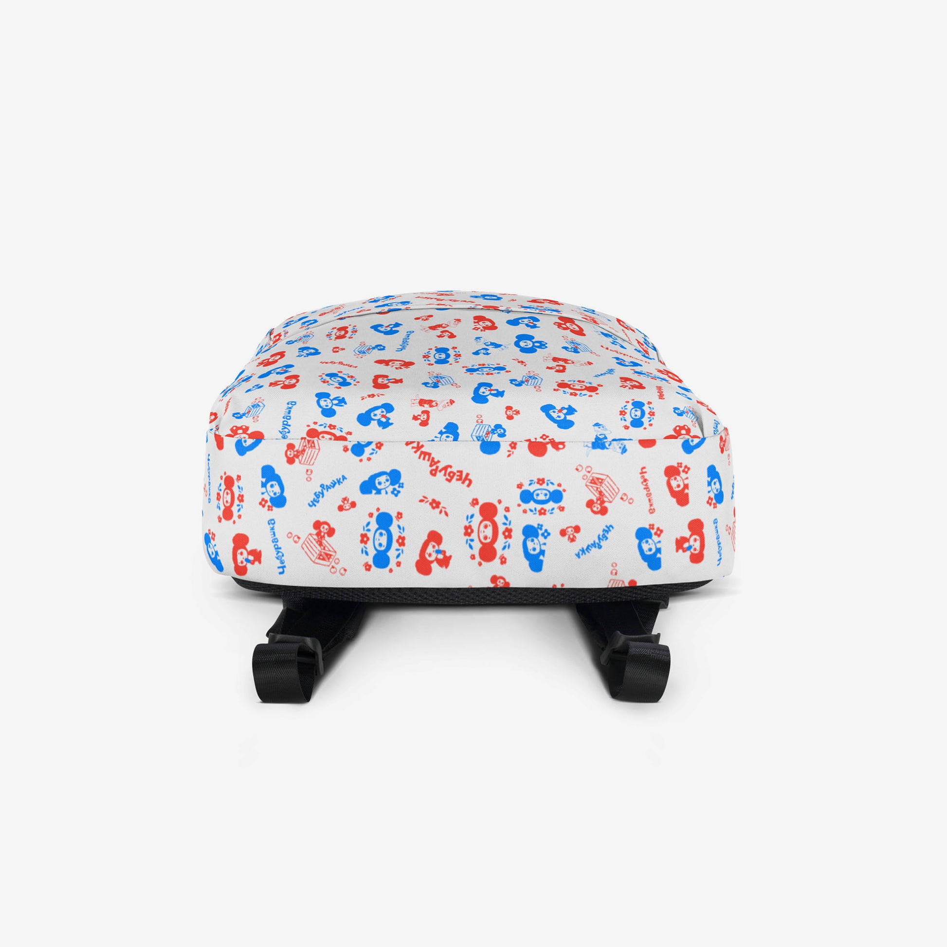 A white backpack with a front pocket, featuring all over print pattern of the Soviet cartoon character Cheburashka in blue and red. Bottom side.