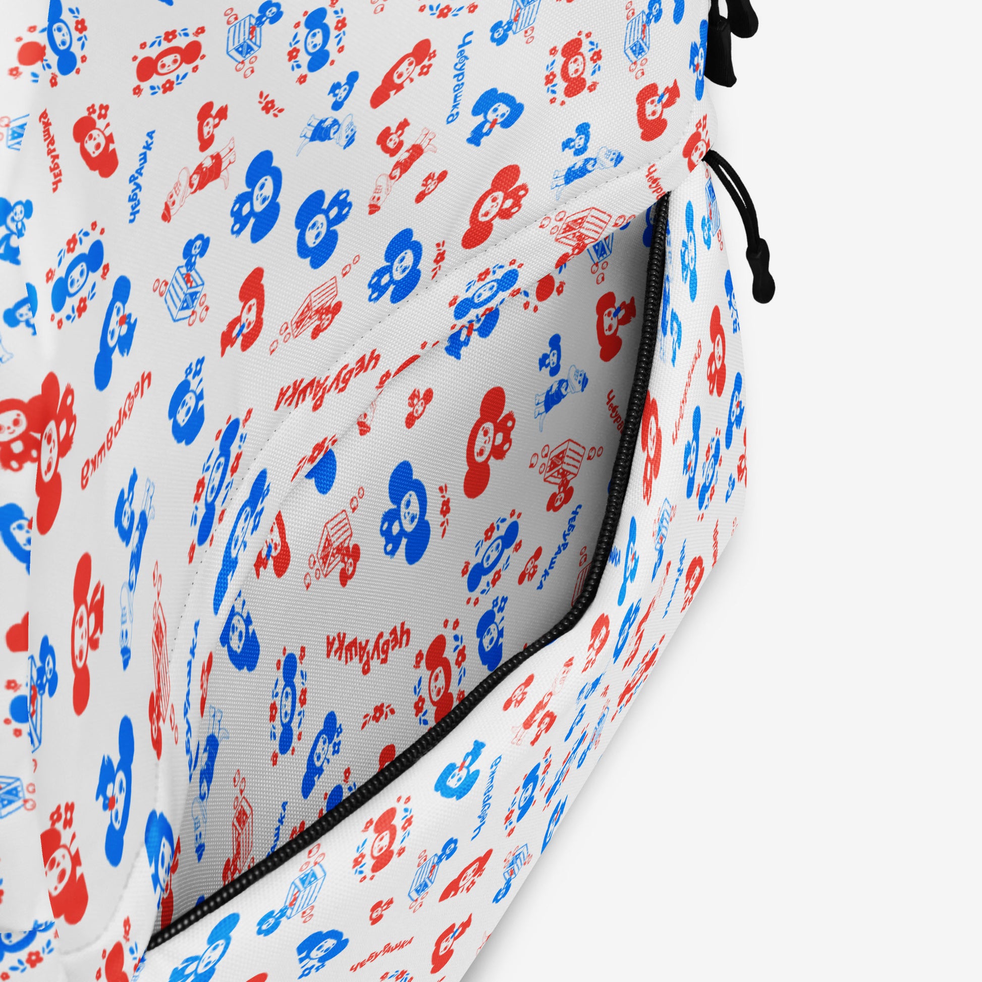 A white backpack with a front pocket, featuring all over print pattern of the Soviet cartoon character Cheburashka in blue and red. Front side pocket.