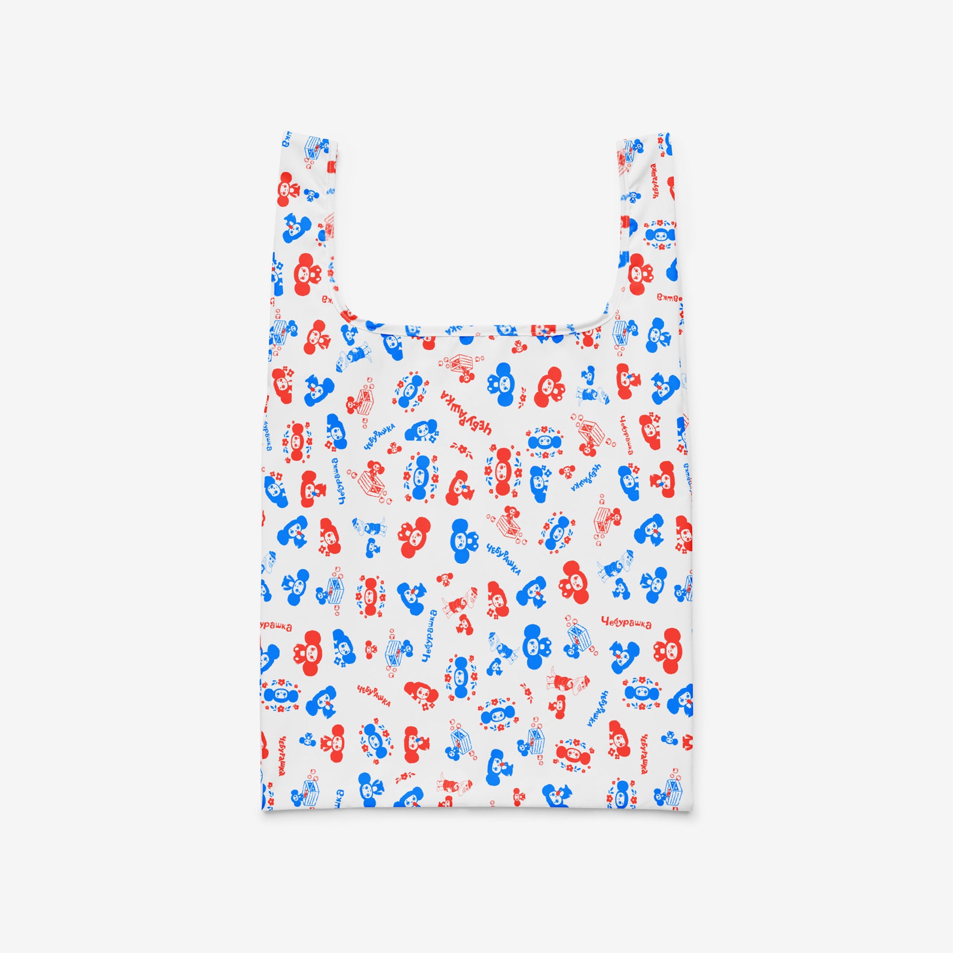 A reusable folding shopping bag with a white background and an all-over pattern of red and blue Soviet cartoon character Cheburashka. Front.