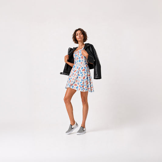 Cute sexy young model girl with long legs wearing short white Cheburashka skater dress, leather jacket and Vans slip on shoes. Dress is with Soviet cartoon character pattern in blue and red over white background.